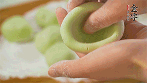 將均分的艾草面團搓成圓，挖一個窩，放入餡心，再搓成圓。