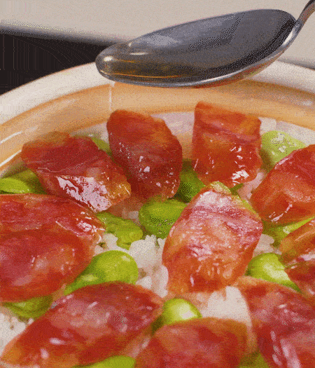 大米出現(xiàn)小孔時(shí)開蓋放香腸，往鍋邊淋入少許油，再燜煮8~10分鐘左右。