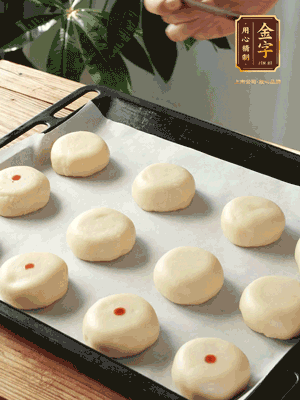 收口向下放在案板上，輕輕將月餅坯按扁，用筷子點紅點做裝飾